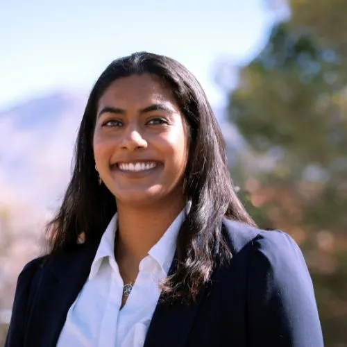 a photo of a smiling woman in a white shirt and dark jacket